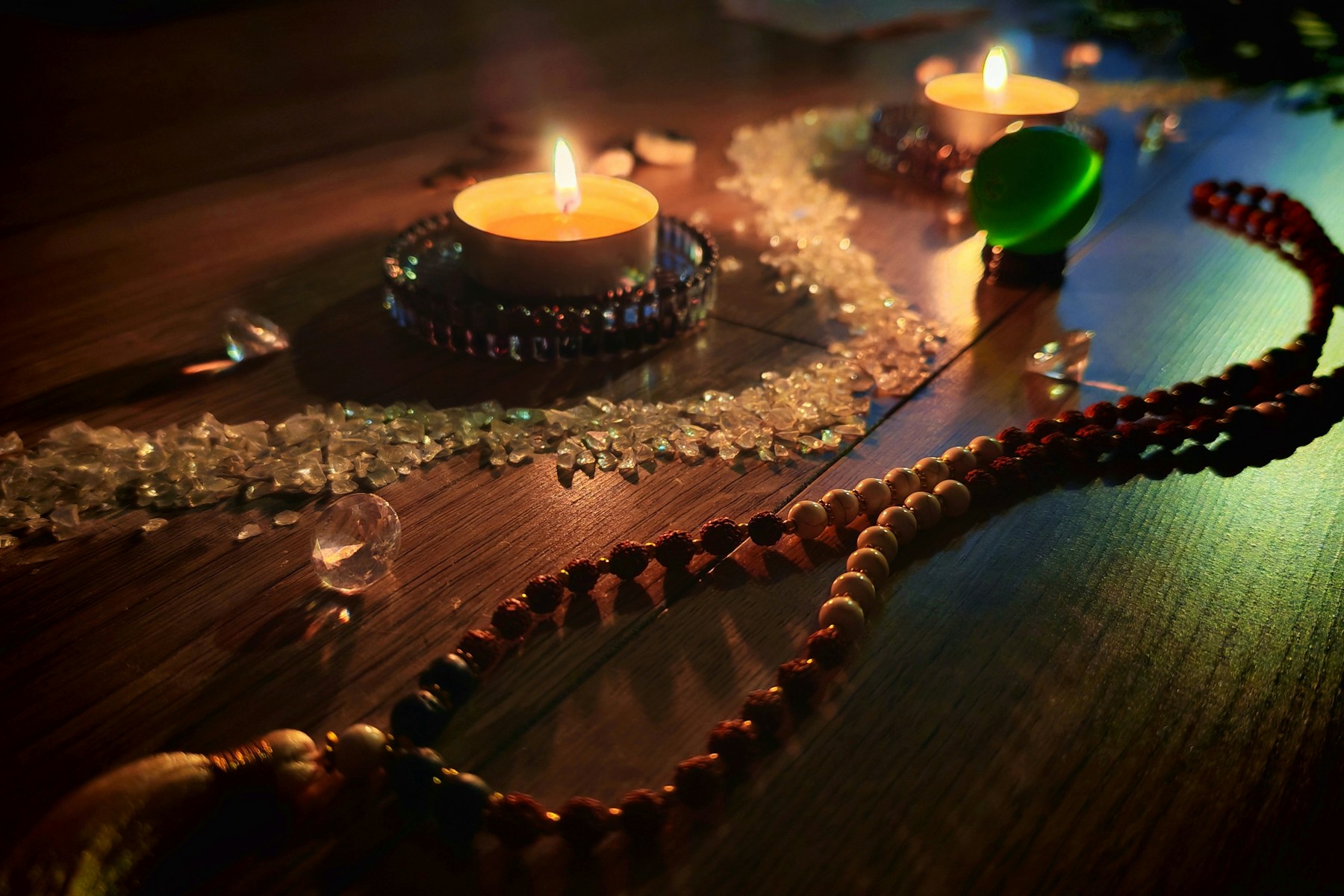 Candles and crystals arranged on a warm wooden surface