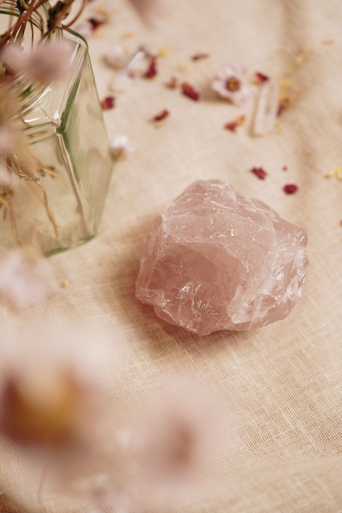 A soft pink polished crystal heart resting on a pale surface
